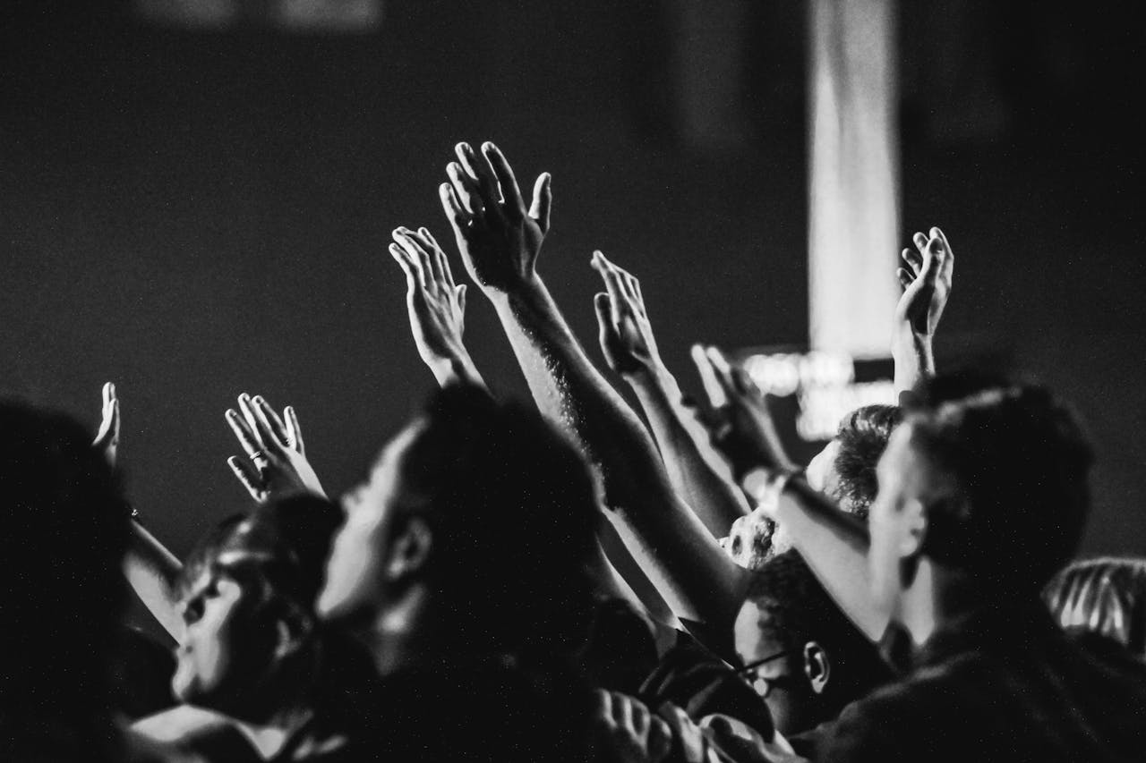 creative-03 Dynamic black and white photo of a concert audience with hands raised, capturing the energy of live music.