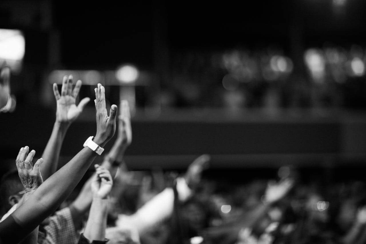 mobile-01 Black and white image of audience with hands raised, capturing concert energy.